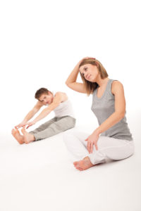Fitness - Healthy couple stretching after training on white background